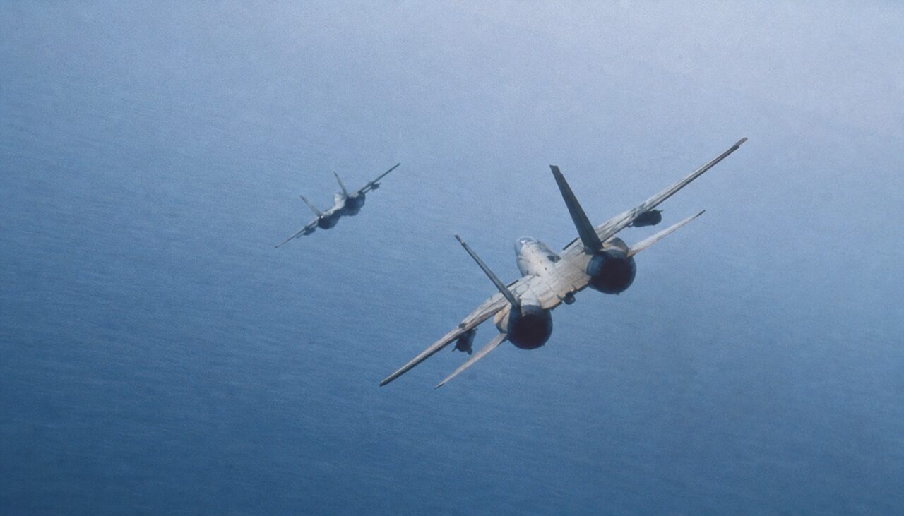 Two Navy fighters descending toward glassy ocean. Textbook conditions: clear sky, no clouds, no horizon clutter.