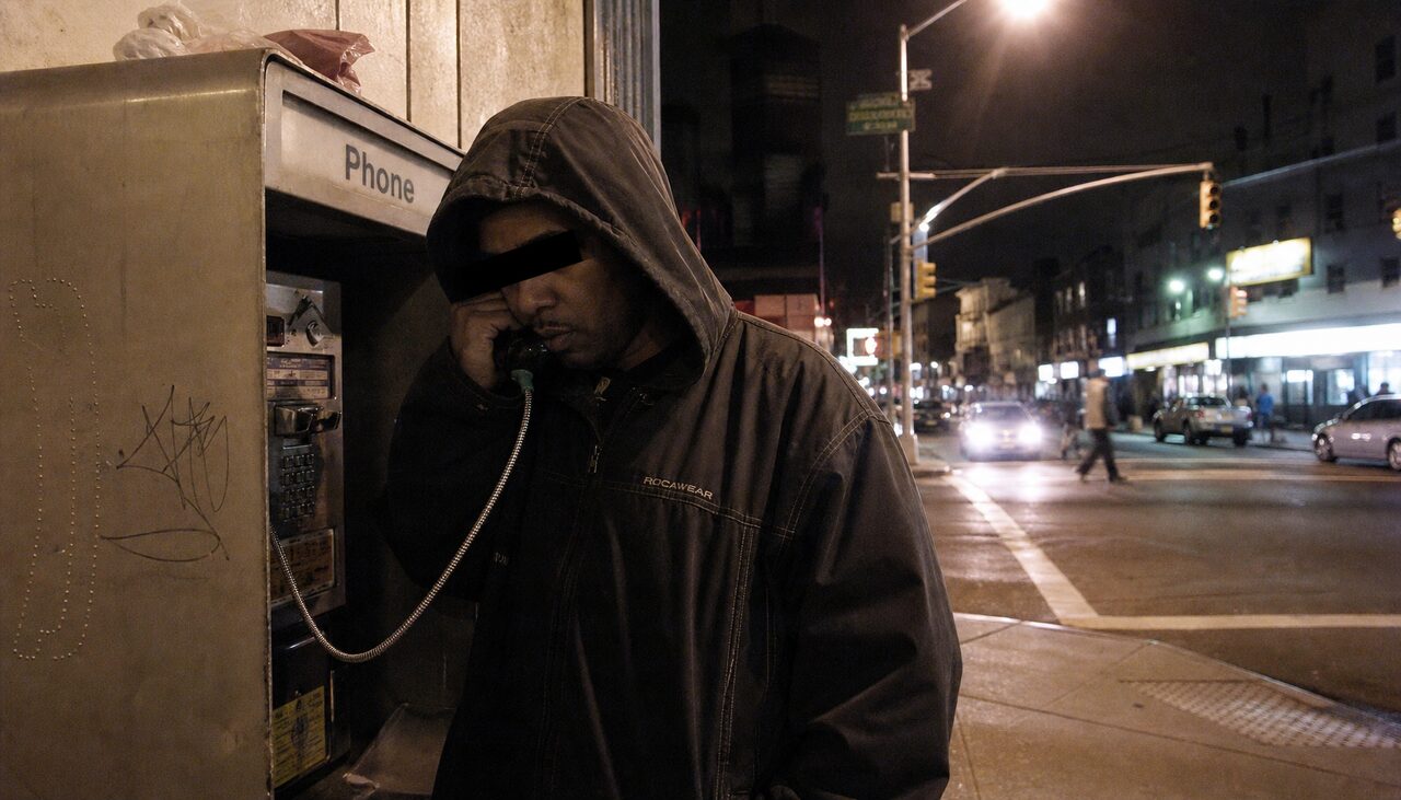 A man at a payphone, declining to be photographed in any useful way.