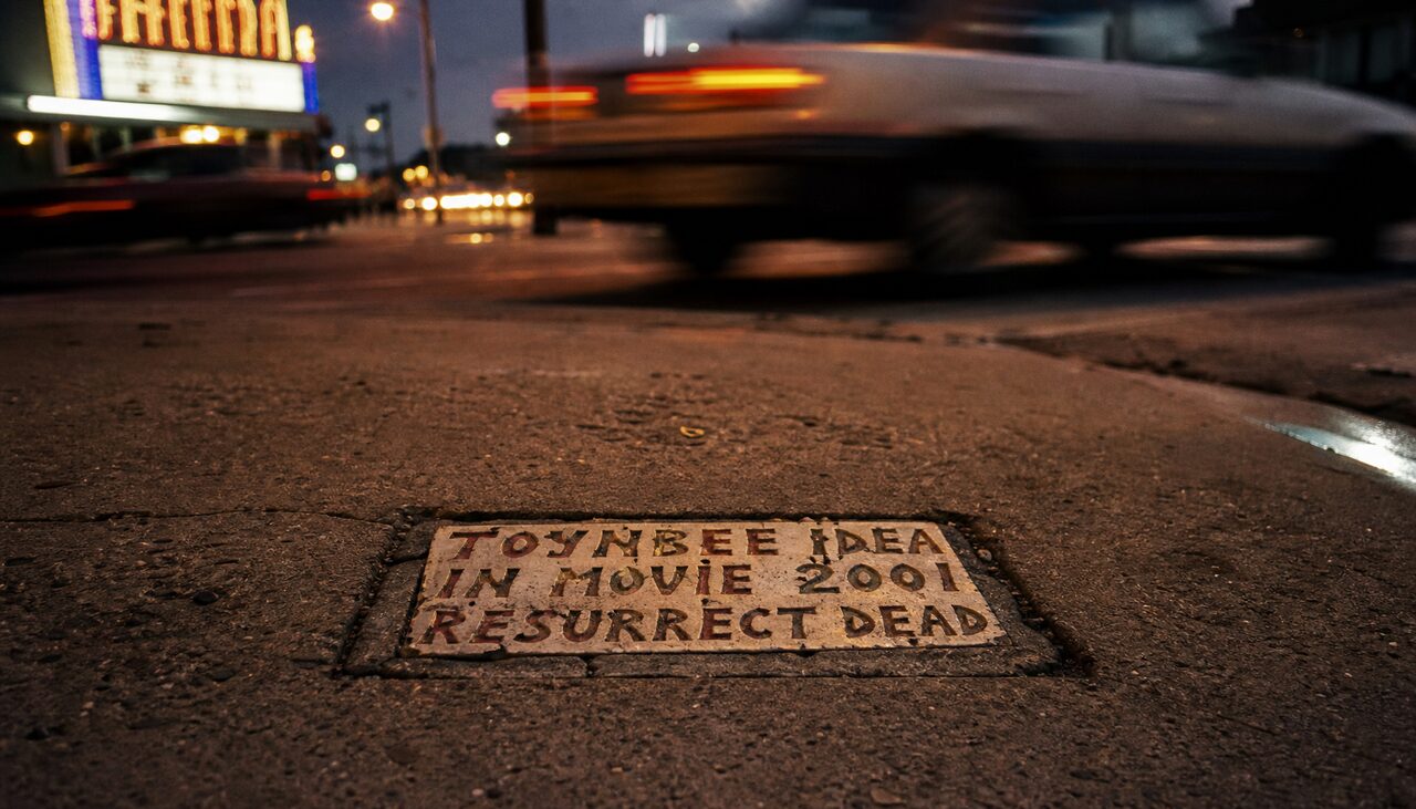 One tile, photographed at street level, dignified despite the setting.