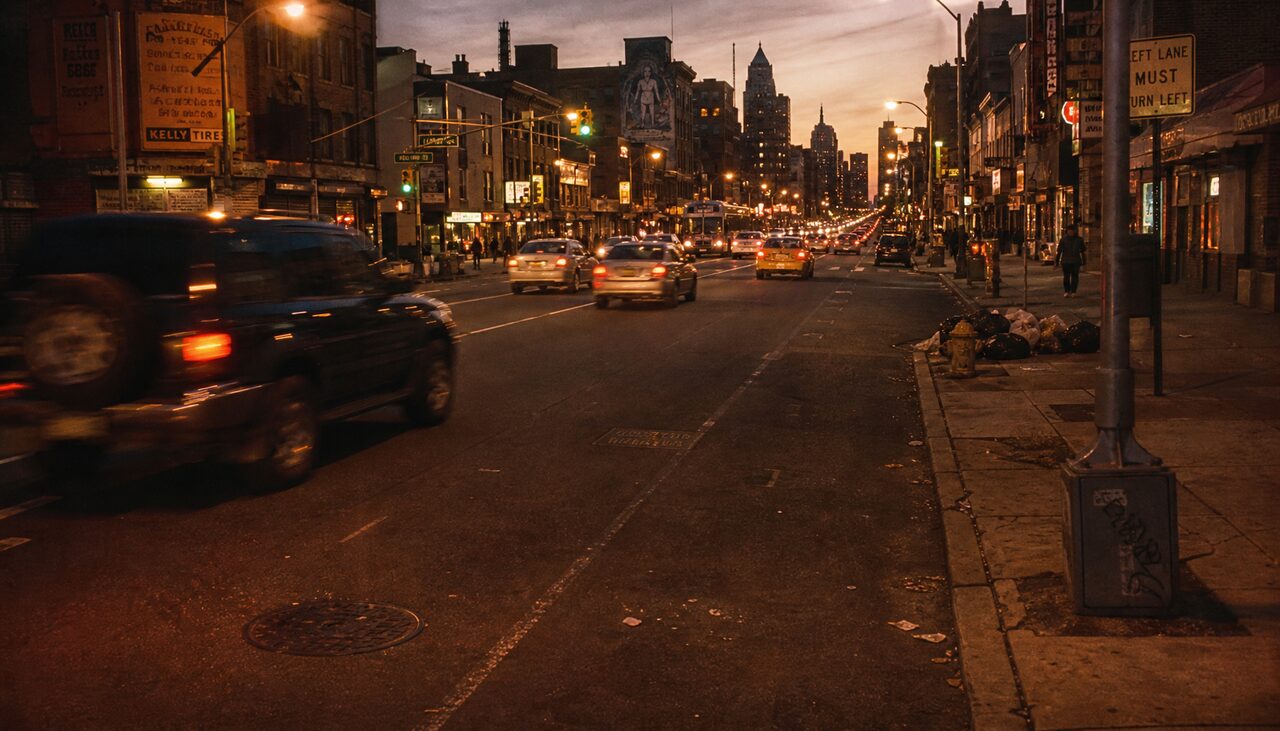 A Philadelphia street at golden hour, one faint rectangle in the asphalt, the city going on without it.
